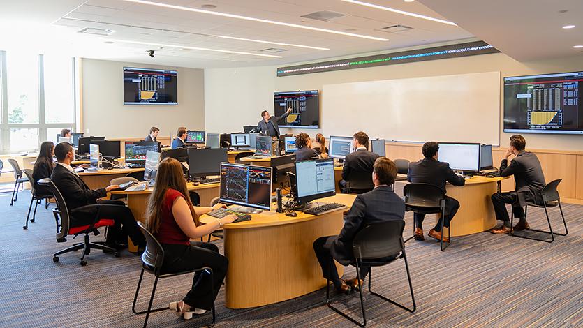 Brian Haughey, Associate Professor of Finance and Director of the Investment Center, discusses financial data with students in the Investment Center on the first floor of the Dyson Center.